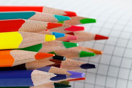 School supplies, a group of colored pencils on the background of a sheet of checkered paperの写真素材