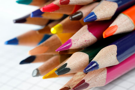 School supplies, a group of colored pencils on the background of a sheet of checkered paperの写真素材