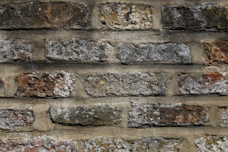 A fragment of a wall made of bricks. Bonds in the masonry wall are visible between bricks and are formed by the mortar filling between layers of bricks.の写真素材