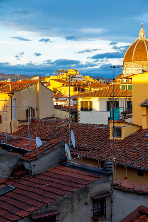 The rays of the setting sun illuminate the roofs of historic houses somewhere in the old town of Florence, Italy.の写真素材