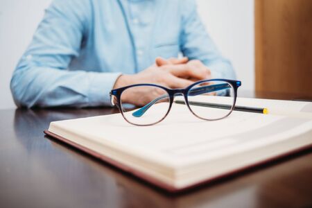 Glasses on book with man hands in office