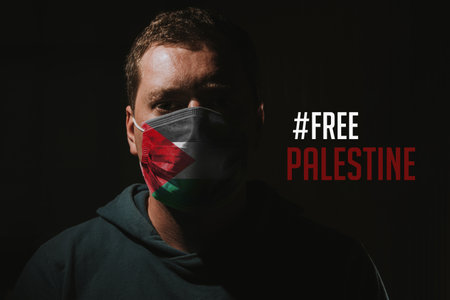 COVID-19 Pandemic. Young man with face mask and flag of Palestine on black background. Coronavirus outbreak concept.の写真素材