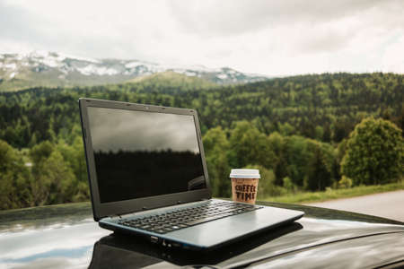 outdoors laptop with coffee cup, remote location in nature with beautiful mountains internet connection, freelancer freedomの写真素材