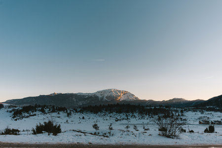 Winter landscape with snow-capped mountains and clear blue sky.の写真素材