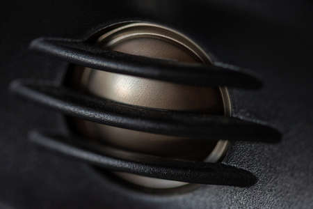 Close-up of a sound speaker with a metal ring on a black background