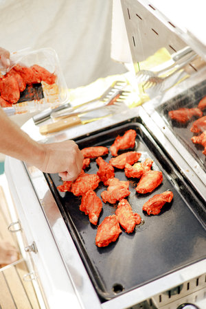 Cooking spicy chicken wings on an electric griddle in a bright kitchen settingの写真素材