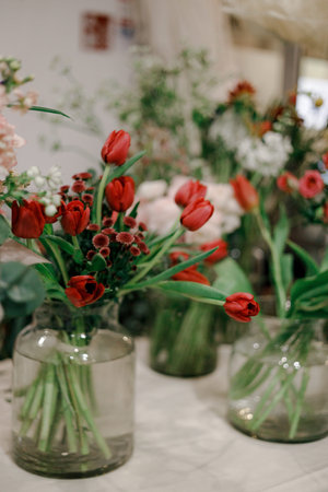 Vase filled with vibrant red tulips and small flowers, soft natural lighting, cozy spring decor, elegant floral arrangement, warm ambianceの写真素材