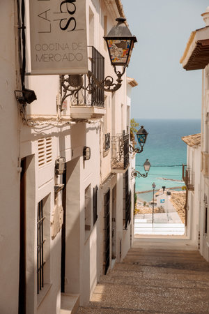 Charming Mediterranean street with historic street lamps overlooking the sea and whitewashed buildingsの写真素材