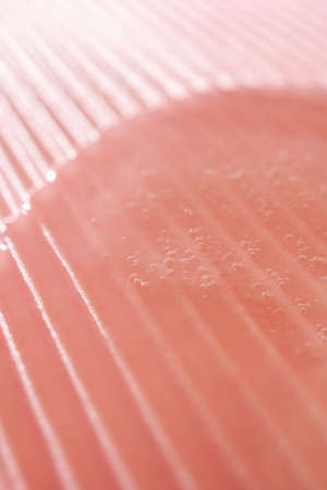 The gel flows over a pink fluted backgroundの写真素材