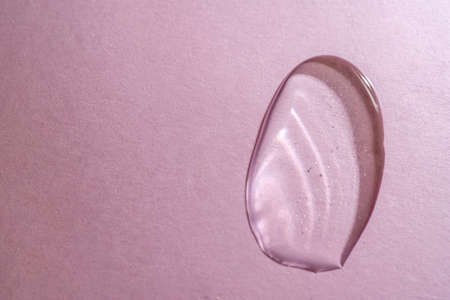 A drop of transparent cosmetic gel on a pink backgroundの写真素材