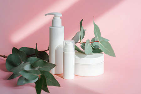Three jars of cosmetics stand on a pink background.の写真素材
