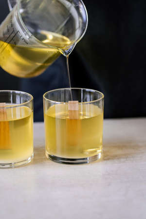The girl pours wax into glass glasses with wicks.の写真素材