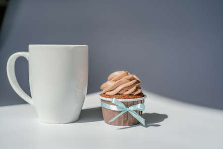 A cupcake or muffin stands next to a cup of coffee.の写真素材