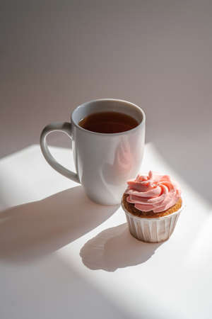 A cupcake or muffin stands next to a cup of coffee.の写真素材