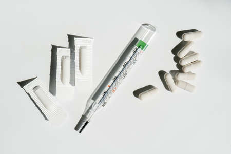 Medicines and a thermometer lie on the white surface of the table.