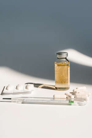 Medicines and a thermometer lie on the white surface of the table.の写真素材