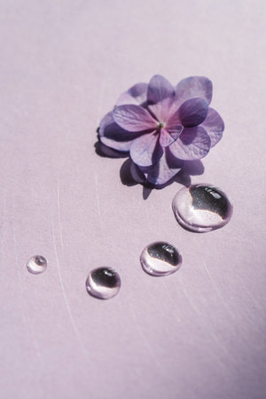 A drop of transparent cosmetic gel with flowers on a purple background.