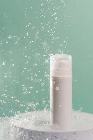 Cosmetic bottle with water splashes on a green background.の写真素材