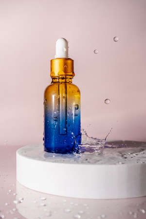 Cosmetic bottles with water splashes on a pink background.の写真素材