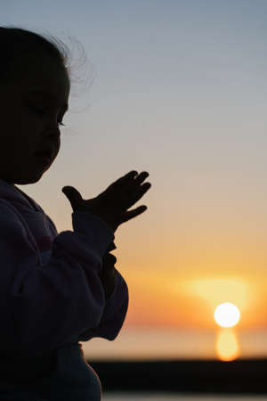 Beautiful sunset on the sea with the silhouette of a child on the backgrounの写真素材
