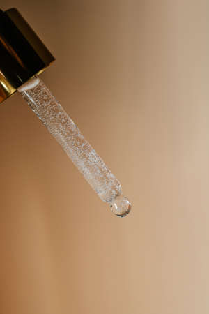 Blue pipette with cosmetic product in water with bubbles.