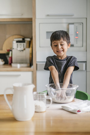The child cooks in the kitchen. Sifts the flour.
