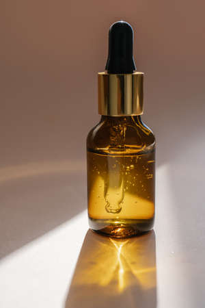 A brown bottle of serum against the beige background..の写真素材