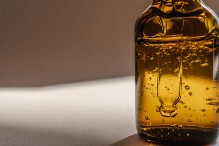 A brown bottle of serum against the beige background..の写真素材