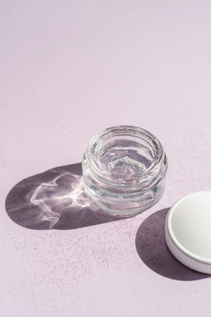 Transparent gel in a jar on a lilac background.