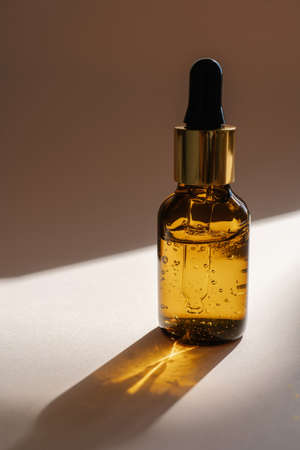 A brown bottle of serum against the beige background..の写真素材