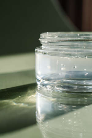 Transparent gel in a jar on a green background.