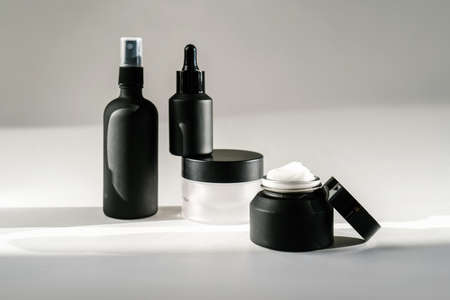 Black cosmetic bottles on a background flooded with sunlight.の写真素材