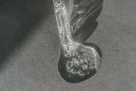 The texture of serum or oil with a pipette on a grey background.