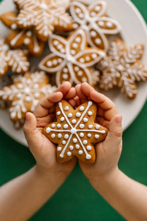 Ginger Christmas cookies in childrens hands on the background of the Christmas tree.の写真素材