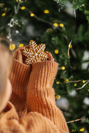 Ginger Christmas cookies in childrens hands on the background of the Christmas tree.の写真素材