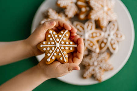 Ginger Christmas cookies in childrens hands on the background of the Christmas tree.の写真素材