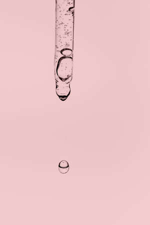 Transparent pipette with cosmetics on a pink background.の写真素材
