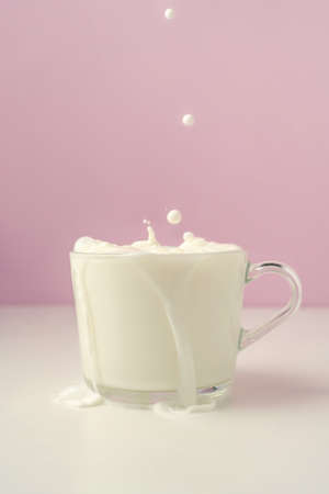 Milk is poured into a transparent cup on a purple background.の写真素材