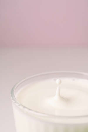 Milk drips into a transparent faceted glass.の写真素材