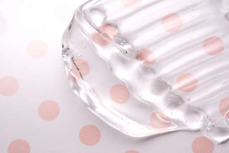 Transparent hyaluronic gel on a pink polka dots background.