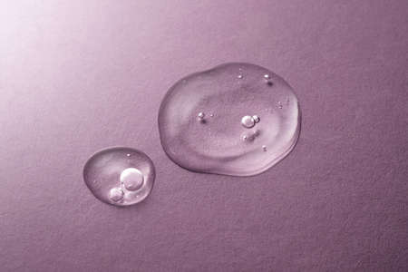 A drops of transparent cosmetic gel on a purple background.