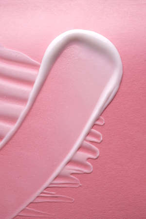 White cream on a pink background. Texture.
