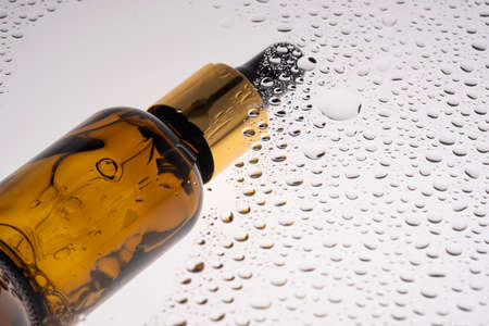 A bottle of cosmetic gel with a pipette on the background of drops.の写真素材