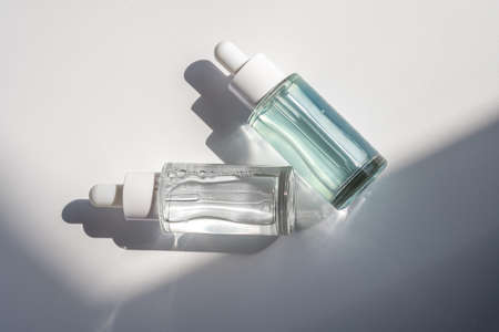 Two laconic bottles of cosmetic liquid in the rays of the harsh sun.