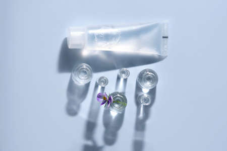 Transparent bottle of cosmetic gel on a blue background with small bottles of water.