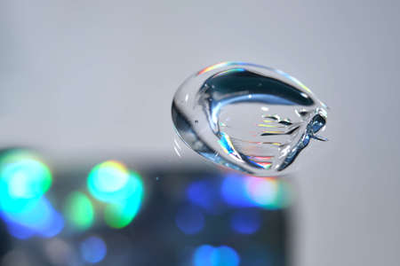 Drop of cosmetic transparent gel on a halographic background. The texture of the serum, heir gel or...