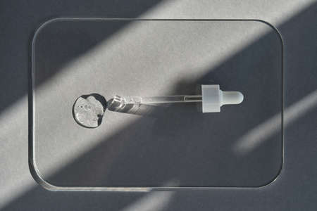 Pipette with spilled cosmetic oil or serum on a gray background.の写真素材