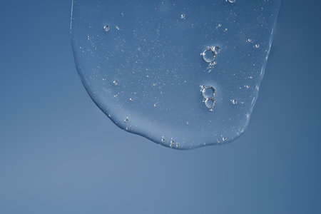 The texture of a gel or shampoo flowing down on a blue background.