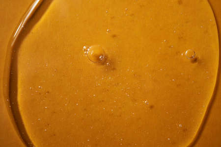 A drop of body gel or shampoo on a yellow saturated background. Texture.