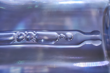 A bottle of serum with a pipette in tinsel in a Christmas theme in purple shades.